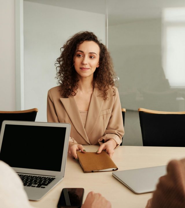 A woman in a business suit participates in a job interview, showcasing professionalism and modern office environment.